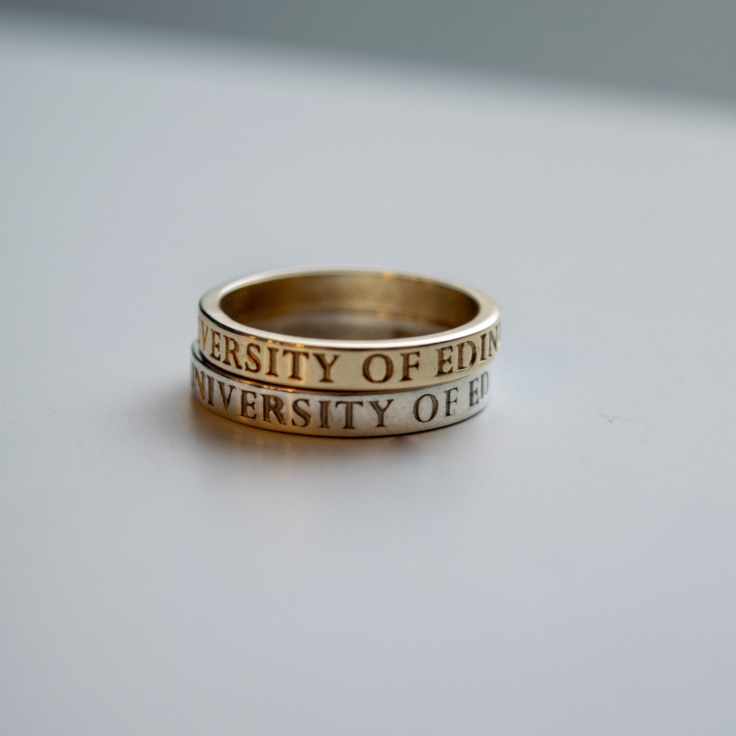 and image of the gold and silver thin band graduation rings on top of each other.