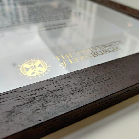 Degree frame detailing demonstrating the University logo in gold foil. 