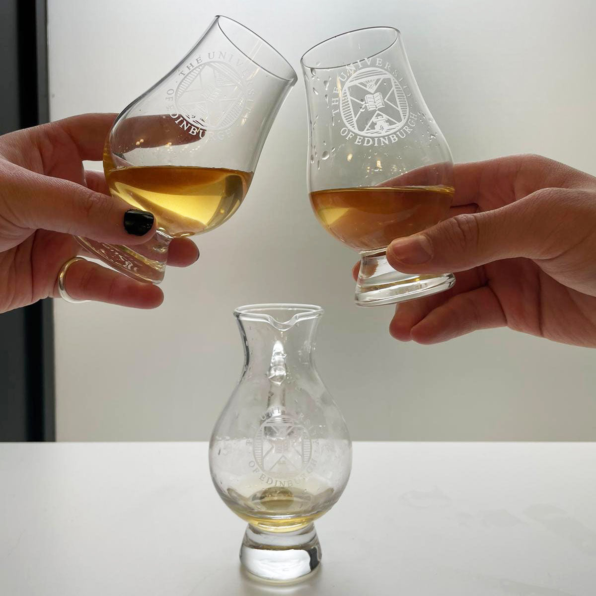 Shot of tasting glasses being toasted over a crystal decanter. 