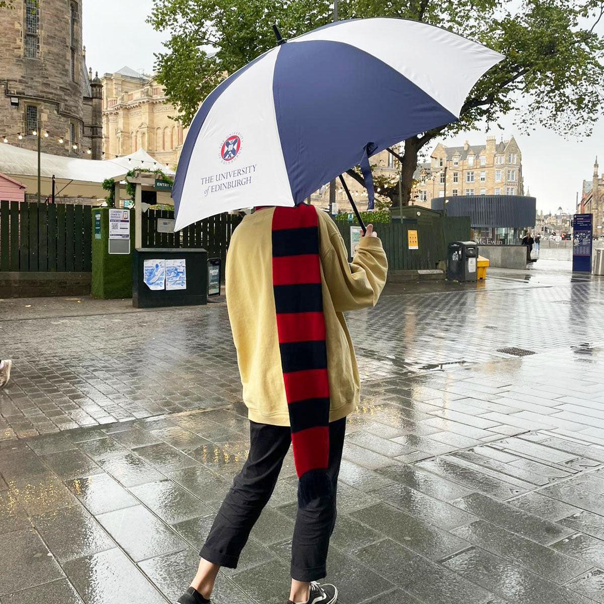 Model in a striped red and navy scarf holding the Large Golf Umbrella. 