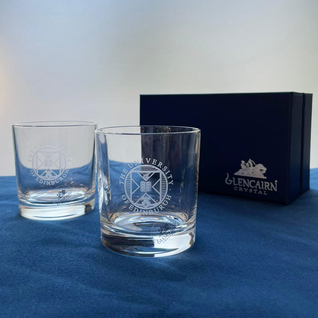Two Crystal whisky glasses with University crest etching displayed in front of a Glencairn presentation box. 