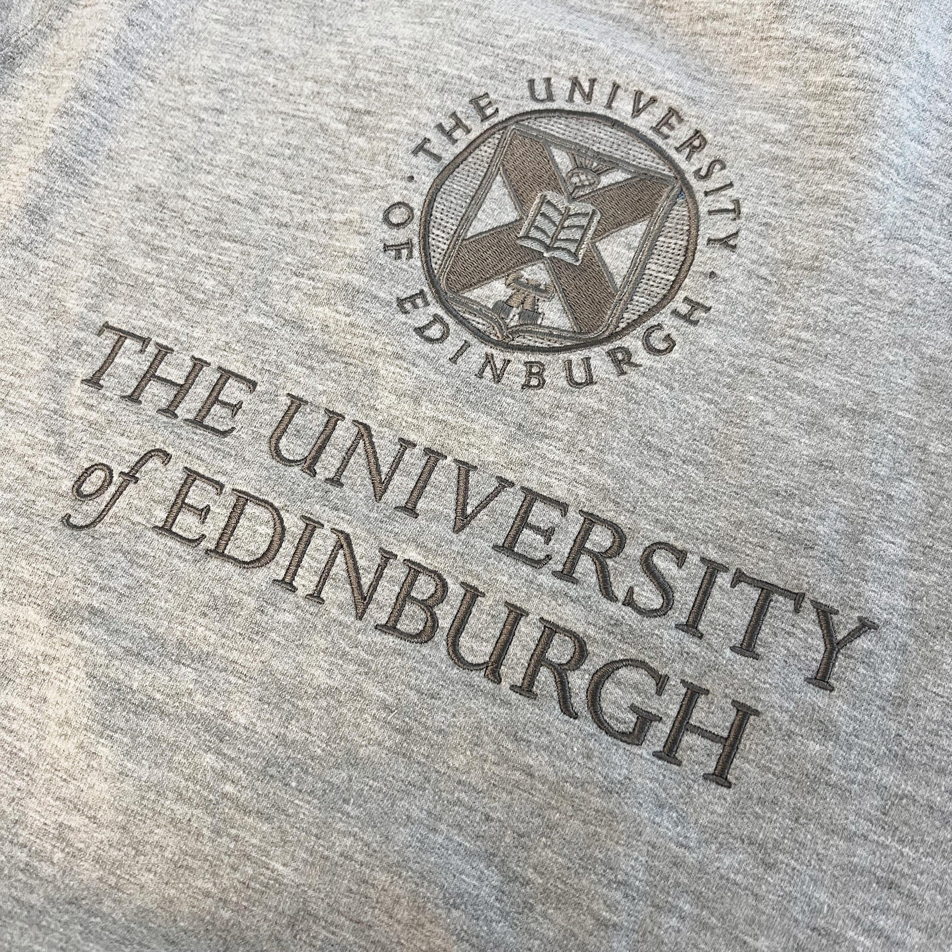 Close up image of the tonal embroidery of the University crest on a grey sweatshirt