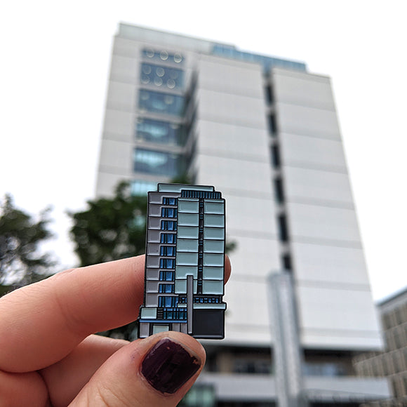 Appleton tower pin badge displayed in front of the real building.