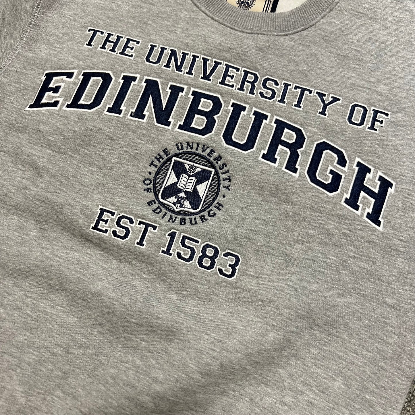 Close up of chest embroidery, which read 'the university of edinburgh, est 1583' and features the university crest in bold navy
