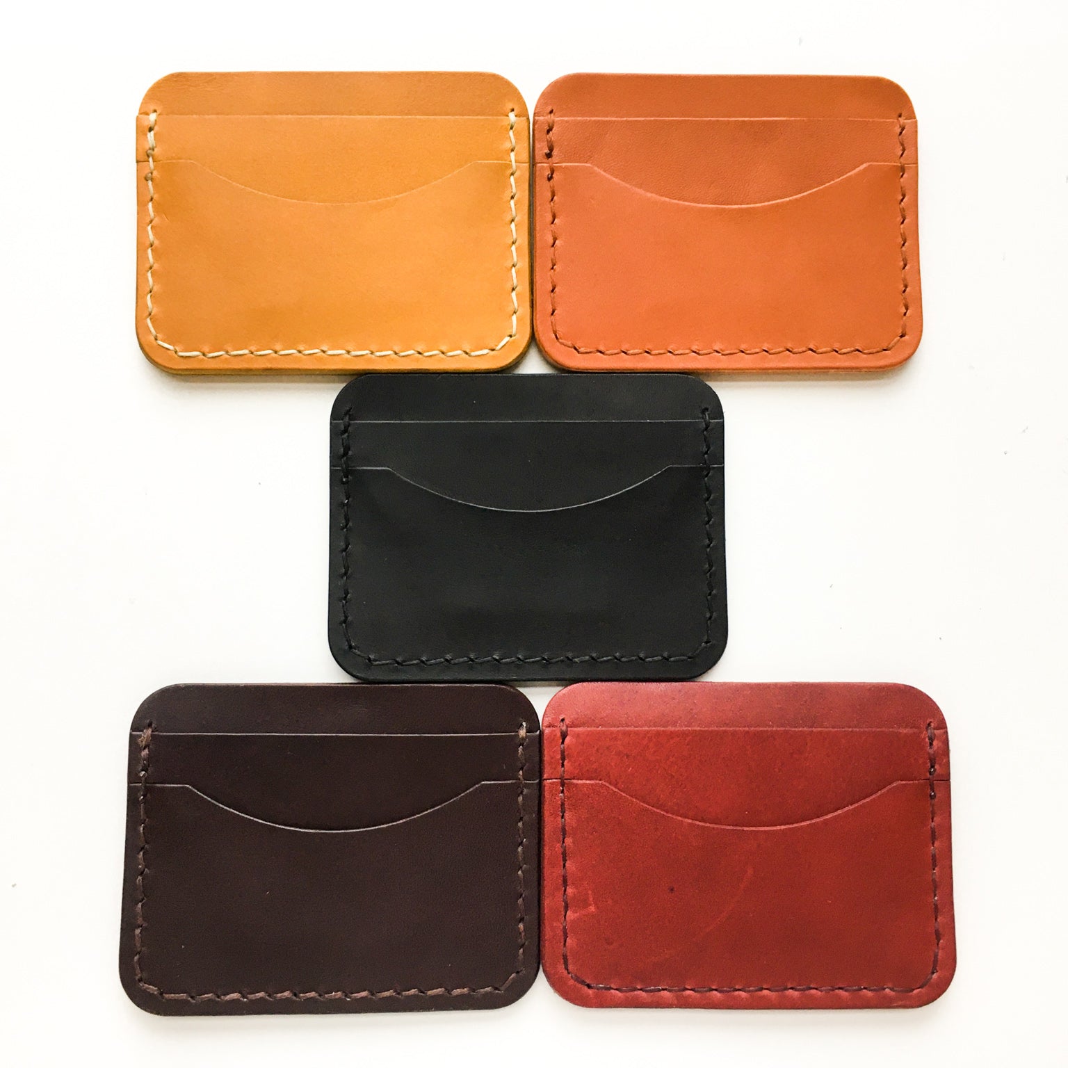 A collection of our leather card holders shot from the back  in mustard, tan, black , brown and red.