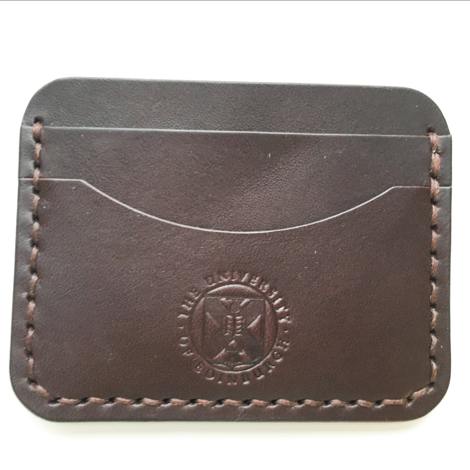 Close up of the brown Leather Card Holder demonstrating the stitching detail and the embossed crest. 