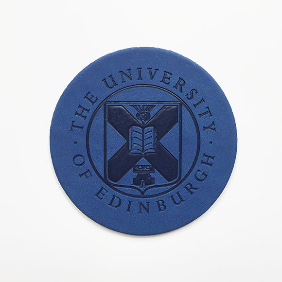 Front view of a leather coaster with embossed University crest in blue
