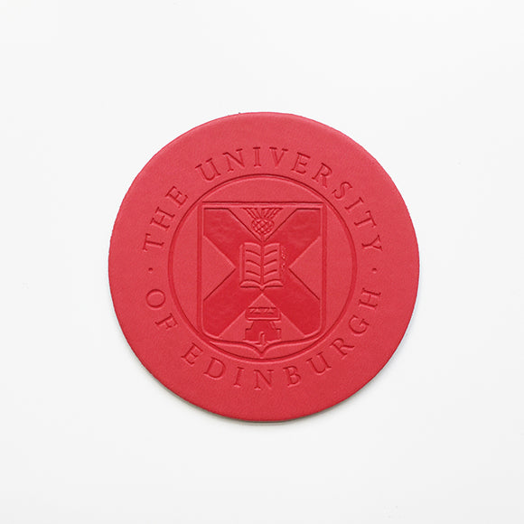 Front view of a leather coaster with embossed University crest in red