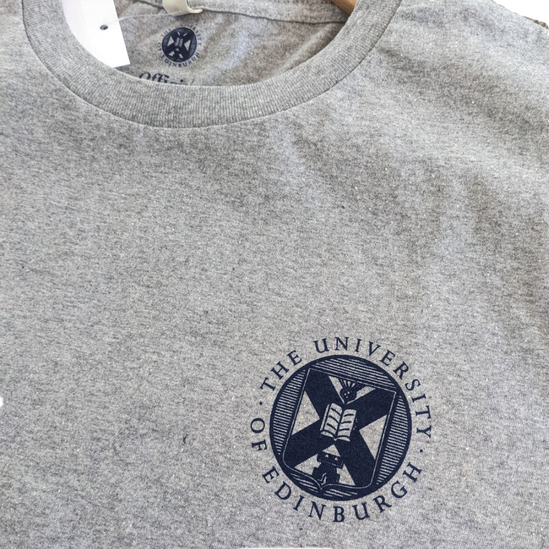 close up image of the crest on A light grey t-shirt with the University crest printed in navy