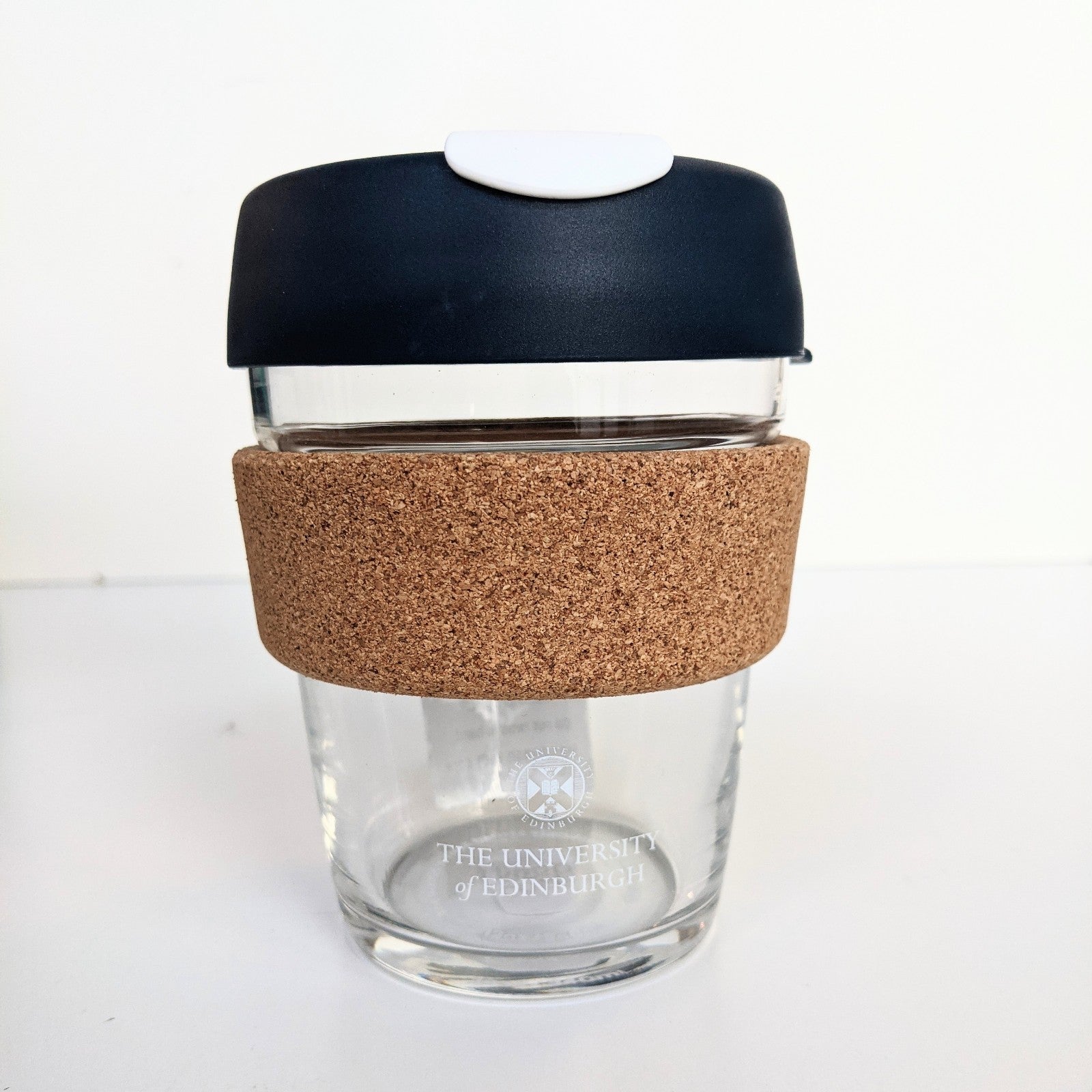 Glass Keep cup with white University branding and cork grip. 