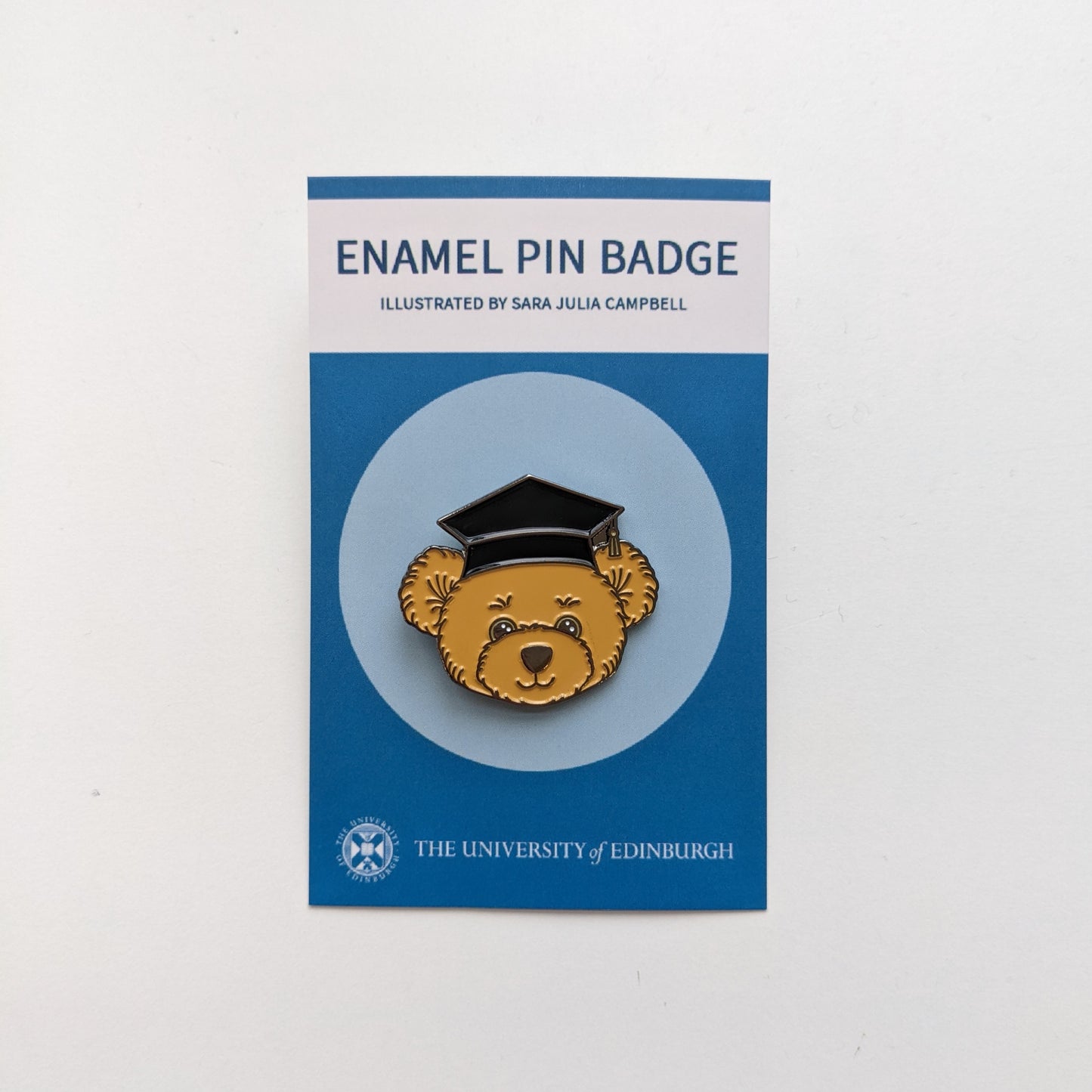 Enamel pin badge of a bear face in a graduation cap. 