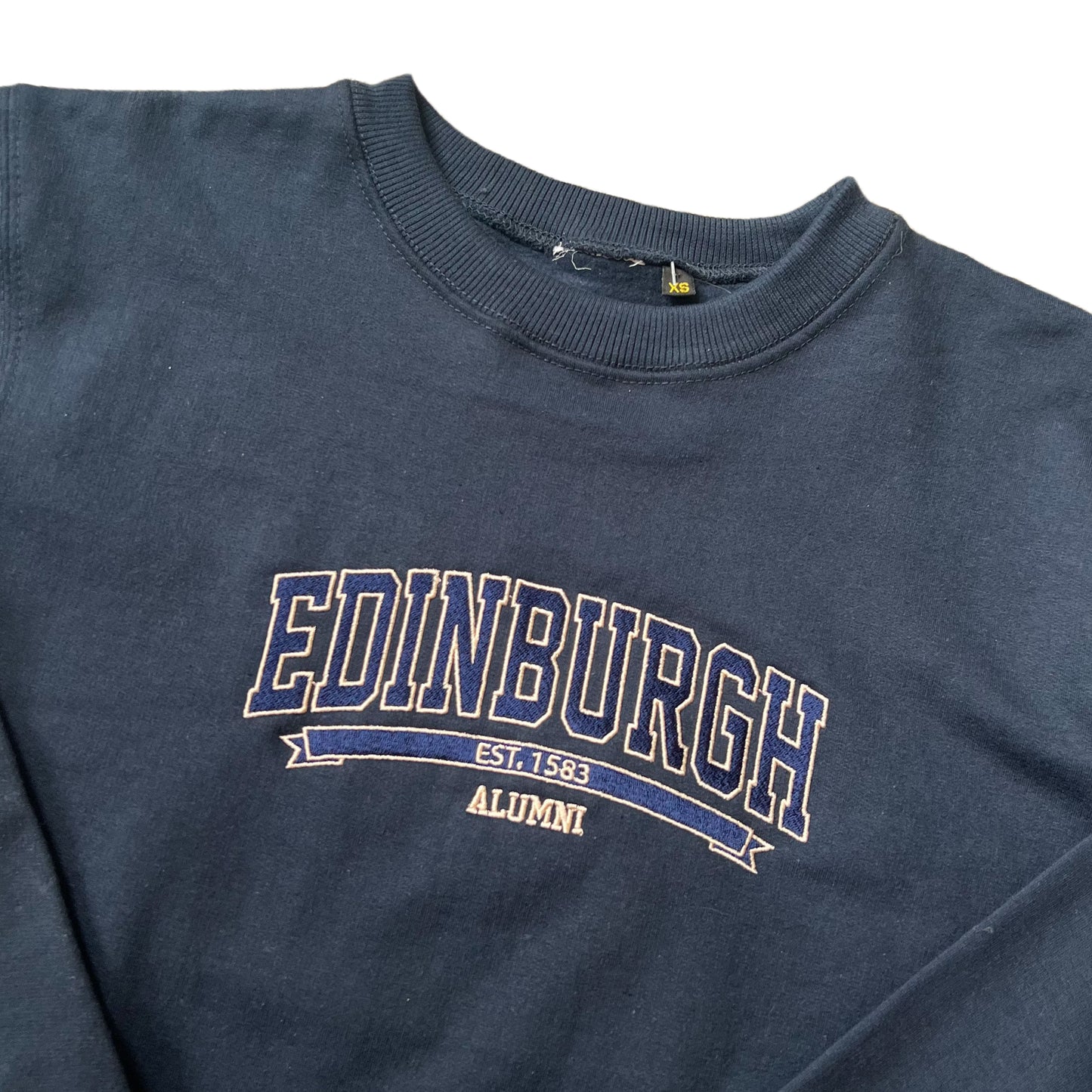 Close up of navy sweatshirt with 'EDINBURGH ALUMNI' stitched on the front in blue and white text