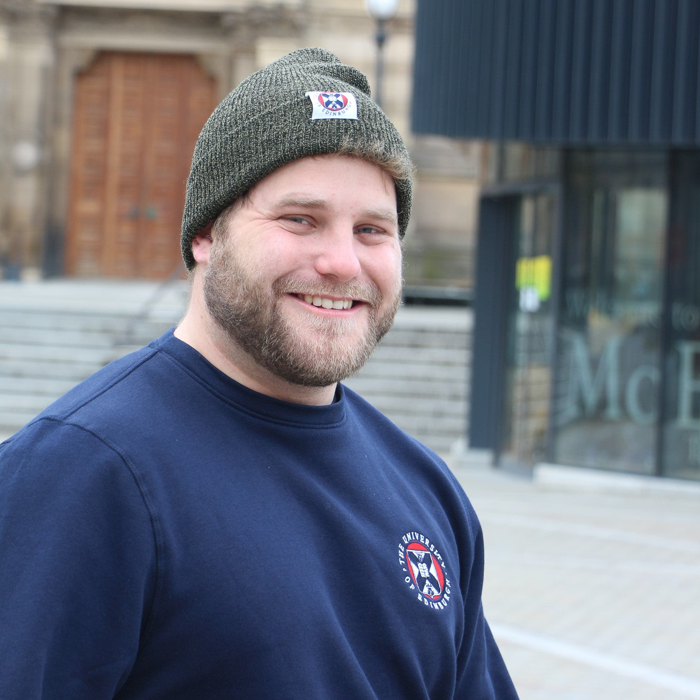Our model wears the heritage style beanie in green and premium embroidered crest sweatshirt in navy
