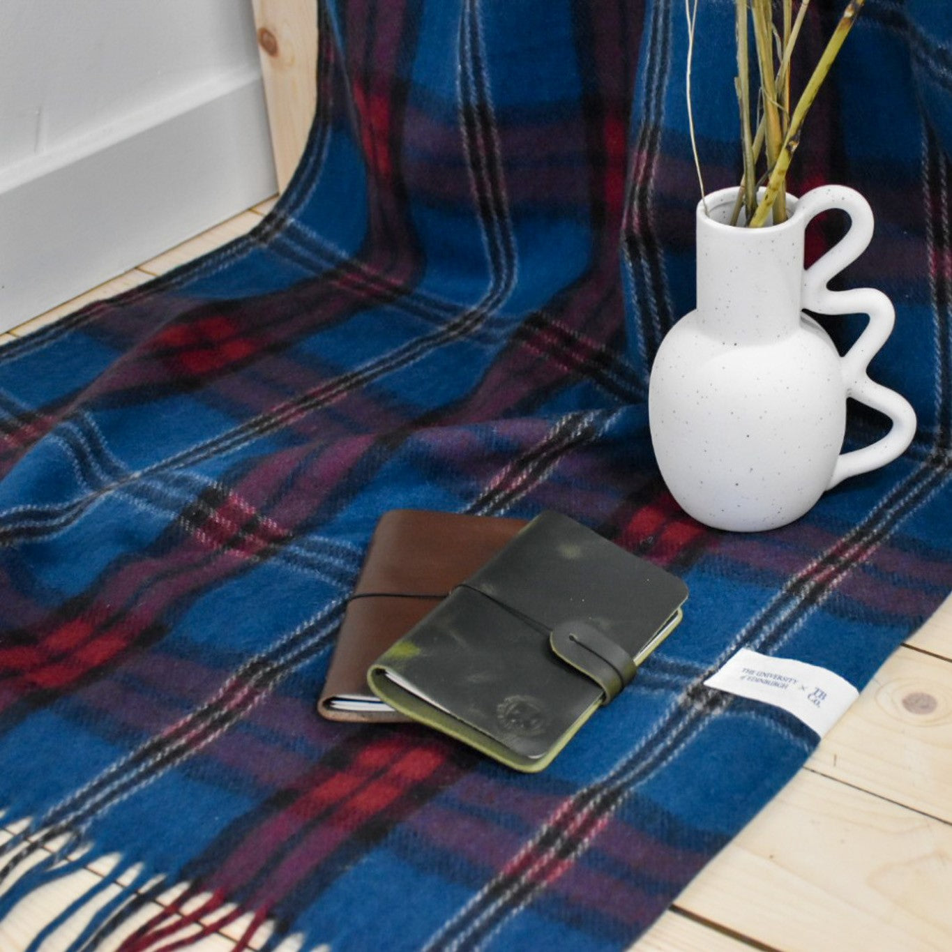 university tartan knee blanket with white vase, and 2 a6 leather notebooks