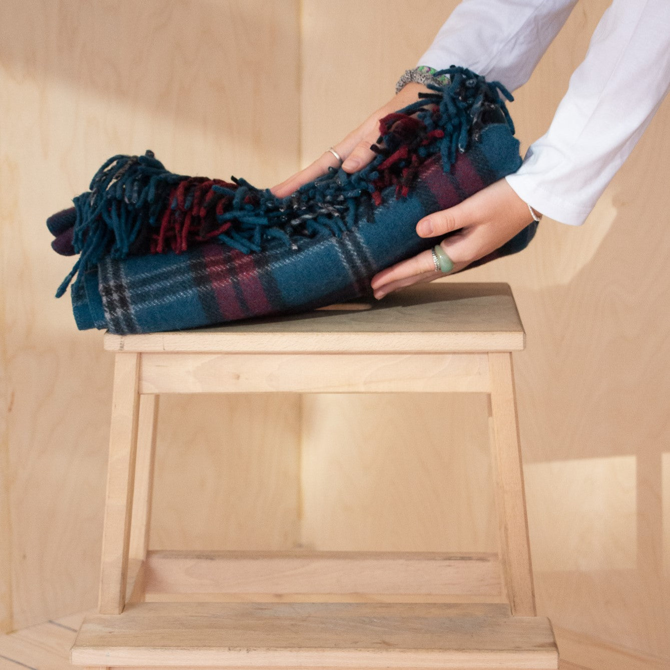 model placing folded knee blanket onto wooden stool