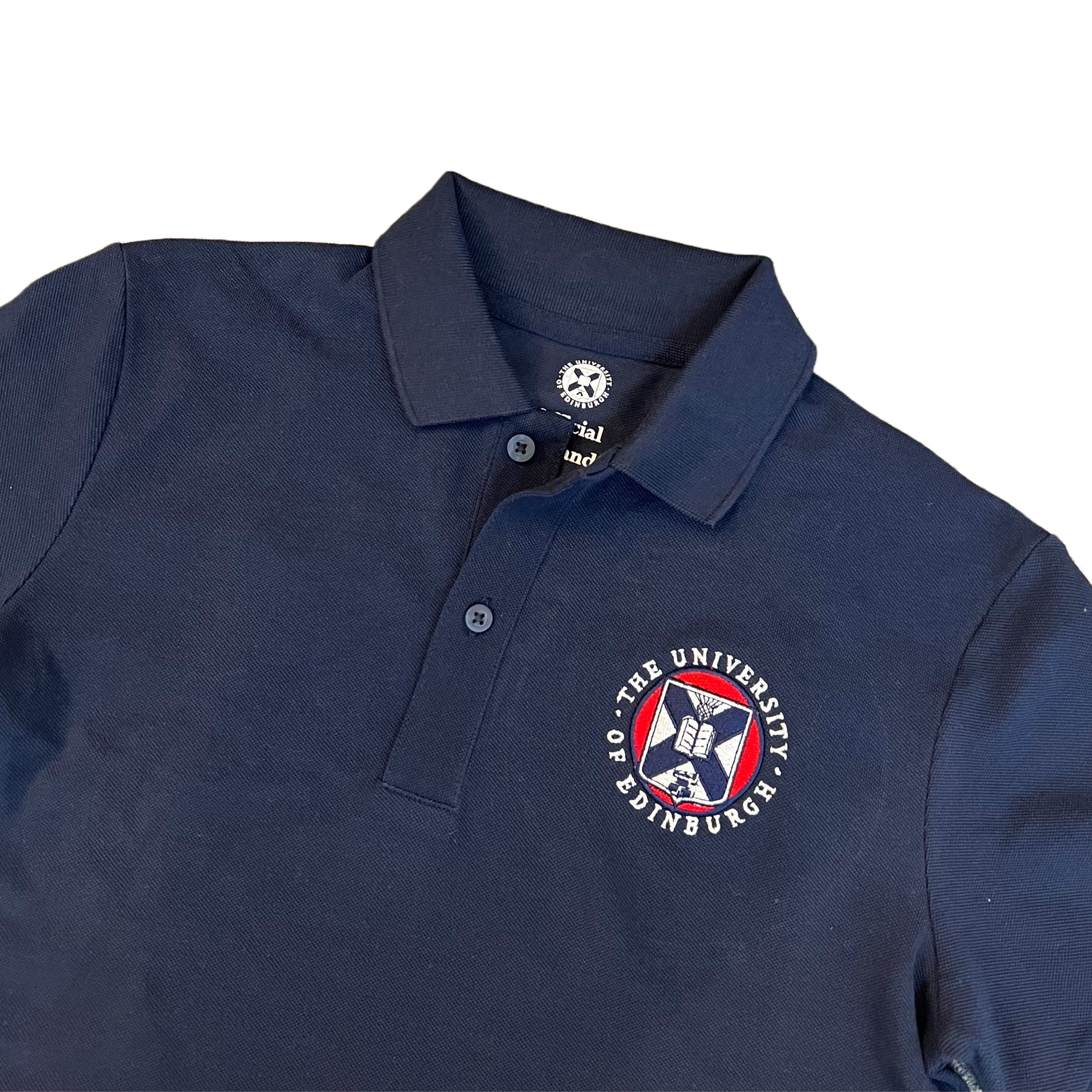 close up of navy polo with university crest embroidered in white, red and navy