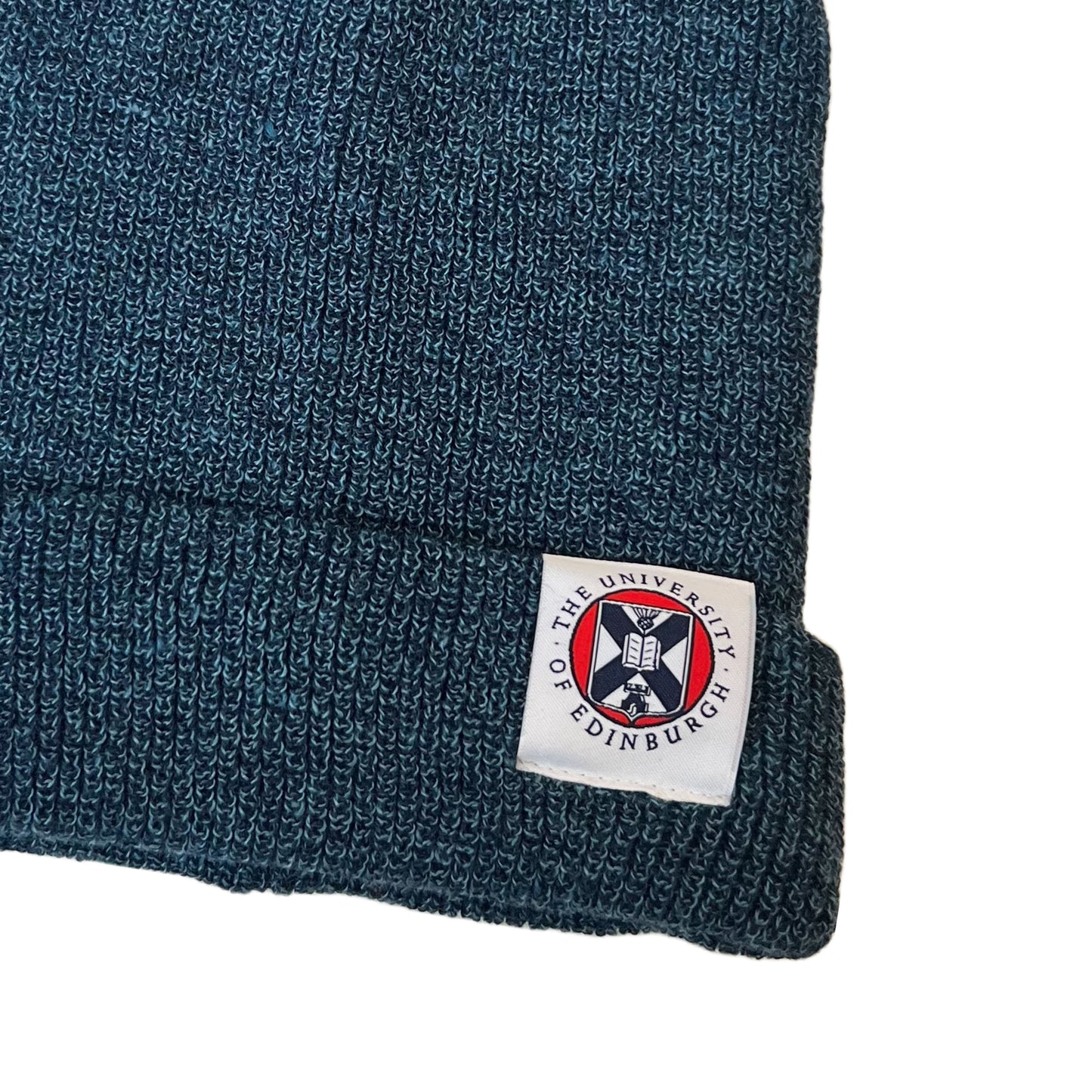 close up of woven tag on petrol blue beanie