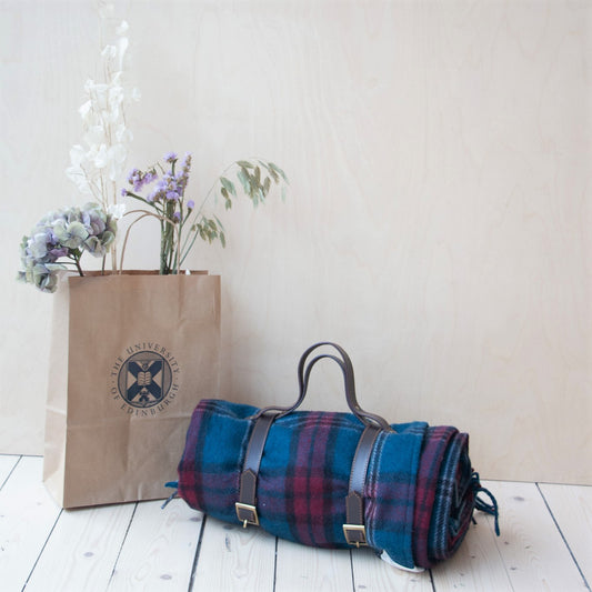 university tartan picnic blanket rolled up in leather carrying strap