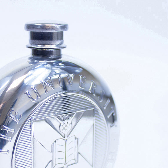 Close up of the embossed University crest on the round pewter hipflask