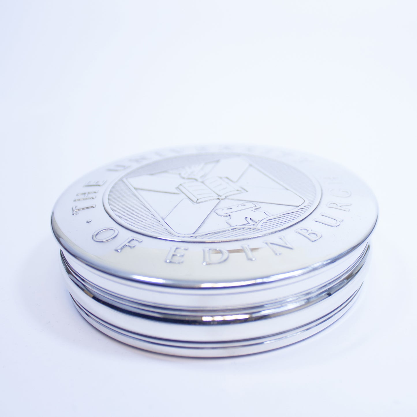 Pewter trinket box with the University crest on the lid as seen diagonally from above